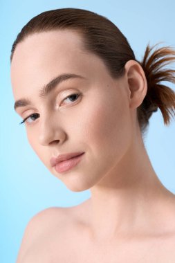 Genç bir kadın, mavi bir zemine karşı şık bir duruşta güzellik ve kendine güven yayar..