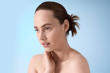 Genç bir kadın zarif bir şekilde eşsiz tarzını yumuşak mavi bir arkaplanda sergiliyor..