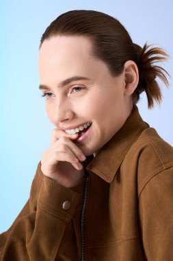 Modaya uygun genç bir kadın dudaklarına neşeyle dokunurken usulca güler ve mutluluk saçar..