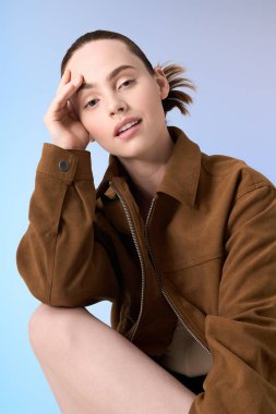 Genç, modaya uygun bir kadın, hafif ışıklandırmada moda bir kıyafet sergilerken düşünceli bir şekilde geriye yaslanır..