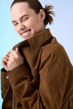 Genç bir kadın gülümsüyor, neşeli bir şekilde ceketini neşeyle düzeltiyor..