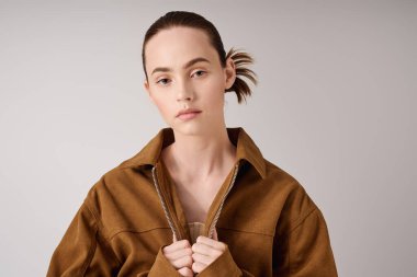 Zarif bir kadın, kahverengi ceketini düzeltirken modern moda eğilimlerini sergiliyor..