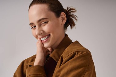 Moda kıyafetleri giymiş genç bir kadın... yavaşça gülümsüyor, kendine güveni ve cazibesi tam..