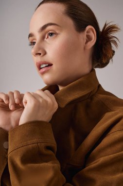 Modaya uygun genç bir kadın zarif bir şekilde poz veriyor, şık elbisesini ve büyüleyici ifadesini vurguluyor.