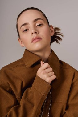 Genç bir kadın şık bir elbiseyle minimalist bir arkaplana ışık saçıyor..