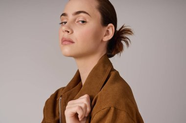 Kendine güvenen genç bir kadın zarif poz verirken modern tarzı moda bir ceketle sergiliyor..