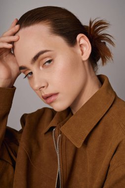 Modayı takip eden genç bir kadın şık bir şekilde poz verir. Yumuşak ışıkta özgüven ve entelektüellik yayar..