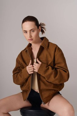 Genç bir kadın modern moda sergiliyor, modaya uygun büyük bir ceket ve dengeli bir tavırla..