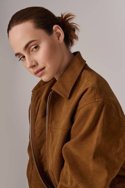 Zarif kahverengi elbiseli güzel bir kadın zarif bir ifade ve duruşla poz veriyor..