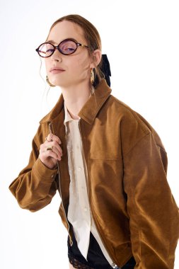 Zarif kahverengi ceketli, şık gözlüklü, kendine güvenen genç bir kadın stil yayıyor..