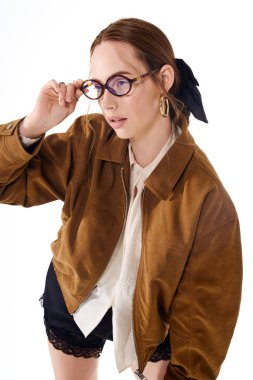 Genç ve güzel bir kadın şık kıyafetler içinde poz veriyor. Cazibeli, zarif ve gözlüklü..