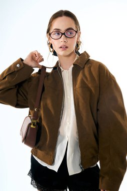 Şık genç kadın kendine güvenerek poz veriyor, şık kıyafetlerini ve kendine güvenen tavırlarını sergiliyor..