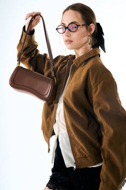 Genç ve güzel bir kadın şık bir çanta tutarken modaya uygun bir görünüm sergiliyor..