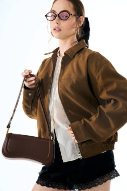 Şık bir genç kadın zarif bir el çantasıyla poz veriyor, modern moda yayıyor..