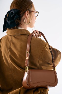 Çekici bir kadın, minimalist bir arka plana karşı şık bir çanta modeller, zarafet saçıyor..