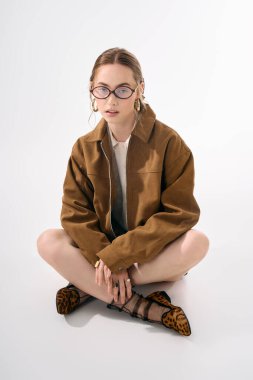 Genç ve güzel bir kadın şık giyinmiş, kendine güveni ve çağdaş cazibesi ile oturuyor..