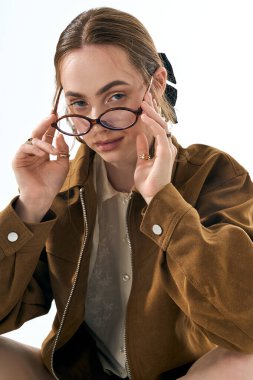 Şık bir iç mekan ortamında, genç bir kadın gözlüğünü kendine güvenen bir ifadeyle ayarlar..