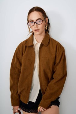 Zarif genç bir kadın, minimalist bir arkaplanda zarif pozlar veriyor, kendine güven ve cazibe saçıyor..