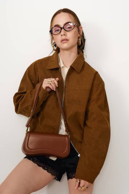 Modaya uygun genç bir kadın şık bir elbiseyle şık bir şekilde poz verir, kendine güveni ve tarzı vardır..