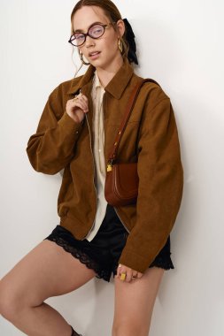 Şık bir ceket ve zarif aksesuarları olan güzel ve genç bir kadın model..