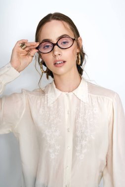 Çekici genç bayan zarif poz veriyor, modern moda tarzında gözlüğünü ayarlıyor..