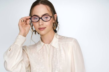 Kendine güvenen genç kadın modaya uygun gözlükleriyle poz veriyor. Benzersiz moda anlayışını ve şık tarzını sergiliyor..