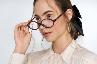 Şık genç kadın, modern moda anlayışını ön plana çıkaran gözlükleriyle zarifçe poz veriyor..