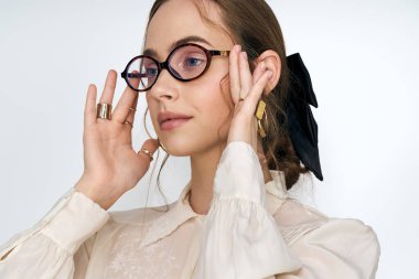 Moda gözlüklü genç kadın kendine has tarzını minimalist bir ortamda sergiliyor..