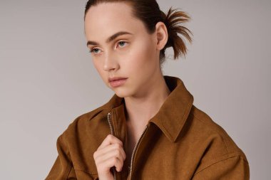 Genç bir kadın şık bir kıyafet ve yoğun bakışlarla eşsiz moda anlayışını sergiliyor..