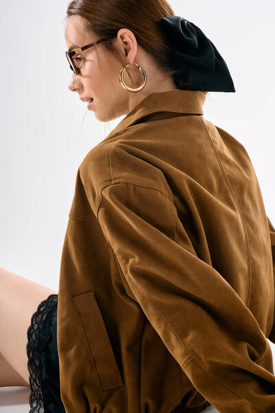 Confident young woman shines in a stylish outfit with oversized accessories in bright light.