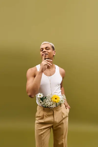 Un joven negro posa con confianza con flores, mostrando su estilo en un estudio. — Stock Photo