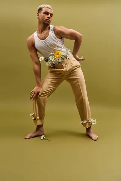 A stylish young man in a tank top poses amid colorful flowers, highlighting youthful fashion. — Stock Photo
