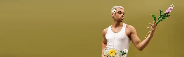 A stylish young man with dyed hair poses confidently in a tank top, adorned with fresh flowers, banner — Stock Photo