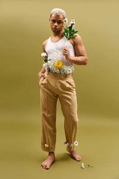 Young man with dyed hair poses confidently in tank top and flowers, exuding modern style. — Stock Photo