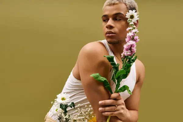 A young african american man showcases his trendy look with dyed hair and flowers in a studio. — Stock Photo