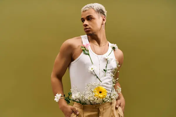 A stylish young man poses in a tank top adorned with flowers, radiating confidence and flair. — Stock Photo