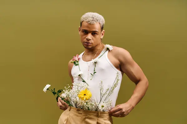 A confident young man poses in a tank top adorned with flowers, radiating style and charm. — Stock Photo