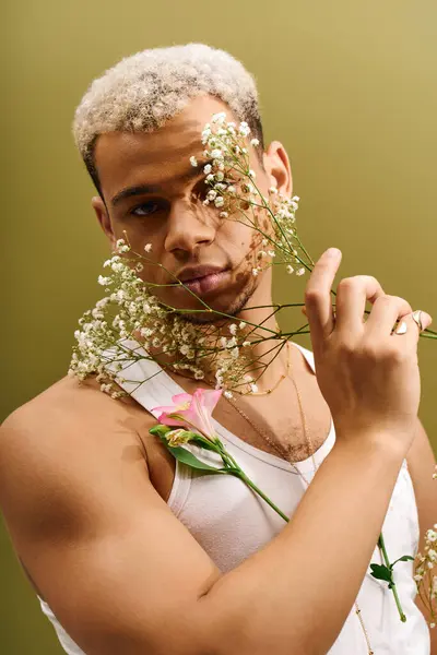A young african american man showcases his unique style while holding flowers in a vibrant studio. — Stock Photo