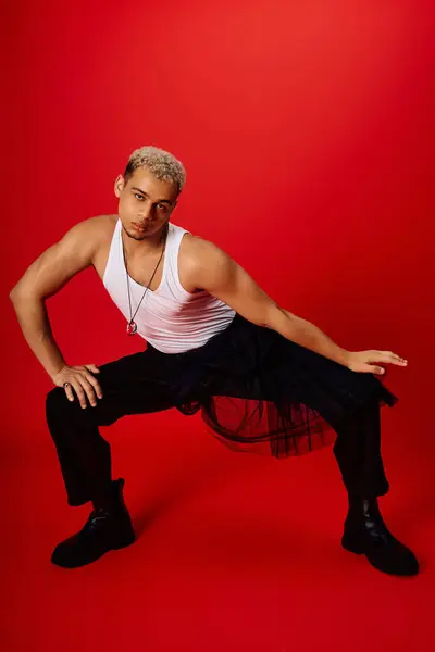 A young Black man in a tank top and pants strikes a dynamic, stylish pose. — Stock Photo