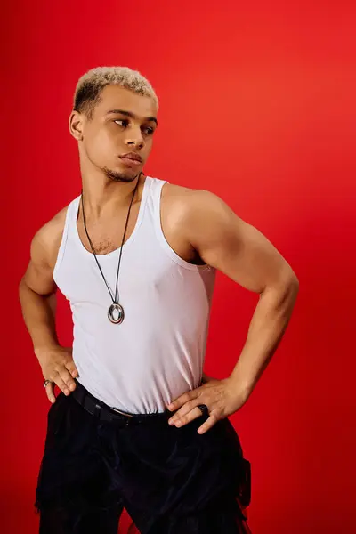 Un joven afroamericano posa con estilo en una camiseta sin mangas y pantalones negros, exudando confianza. - foto de stock