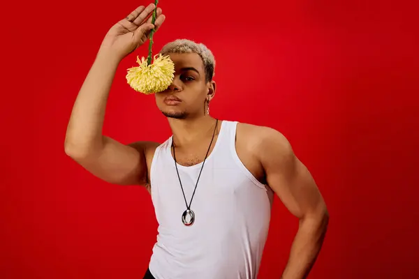 A young African American man poses confidently with a flower against a vibrant red background. — Stock Photo