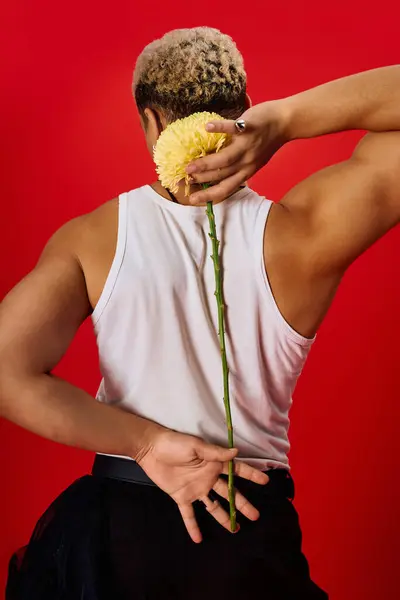 A young African American man showcases his fashion sense with confidence, holding a flower. — Stock Photo