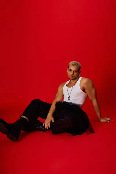A stylish young African American man poses confidently against a vivid red backdrop, exuding charm. — Stock Photo
