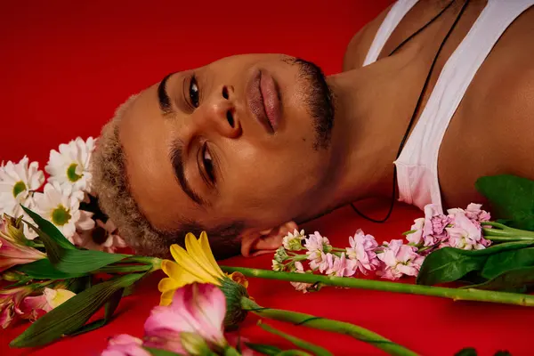 A young Black man relaxes against a colorful backdrop, flaunting his style and confidence. — Stock Photo