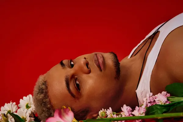 Un jeune Noir aux cheveux teints se détend dans un atelier rouge audacieux, exhibant sa mode. — Photo de stock
