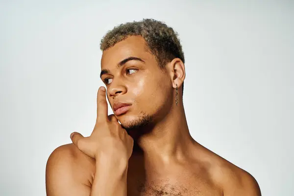 A young African American man exudes confidence posing shirtless in a chic studio. — Stock Photo