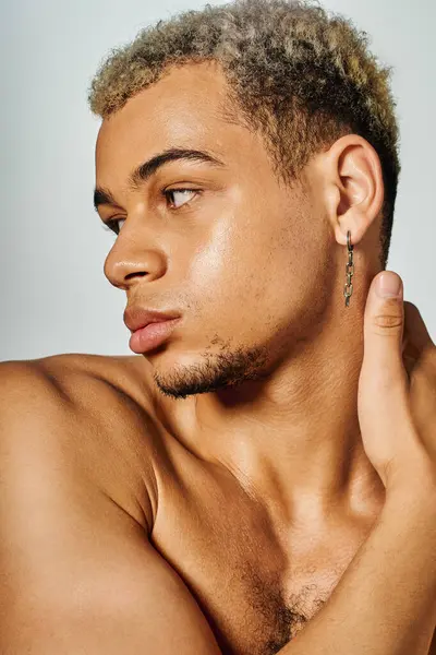 Muscular young man poses gracefully in a studio, highlighting his unique style and beauty. — Stock Photo
