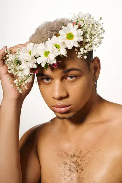 A shirtless man poses elegantly with natural flowers in a bright studio, exuding charisma and style. — стоковое фото