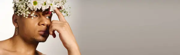 A young Black man poses with floral crown in a bright studio, banner — Stock Photo
