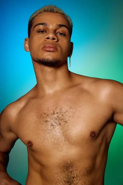 A muscular young African American man poses confidently shirtless against a colorful backdrop. — Stock Photo